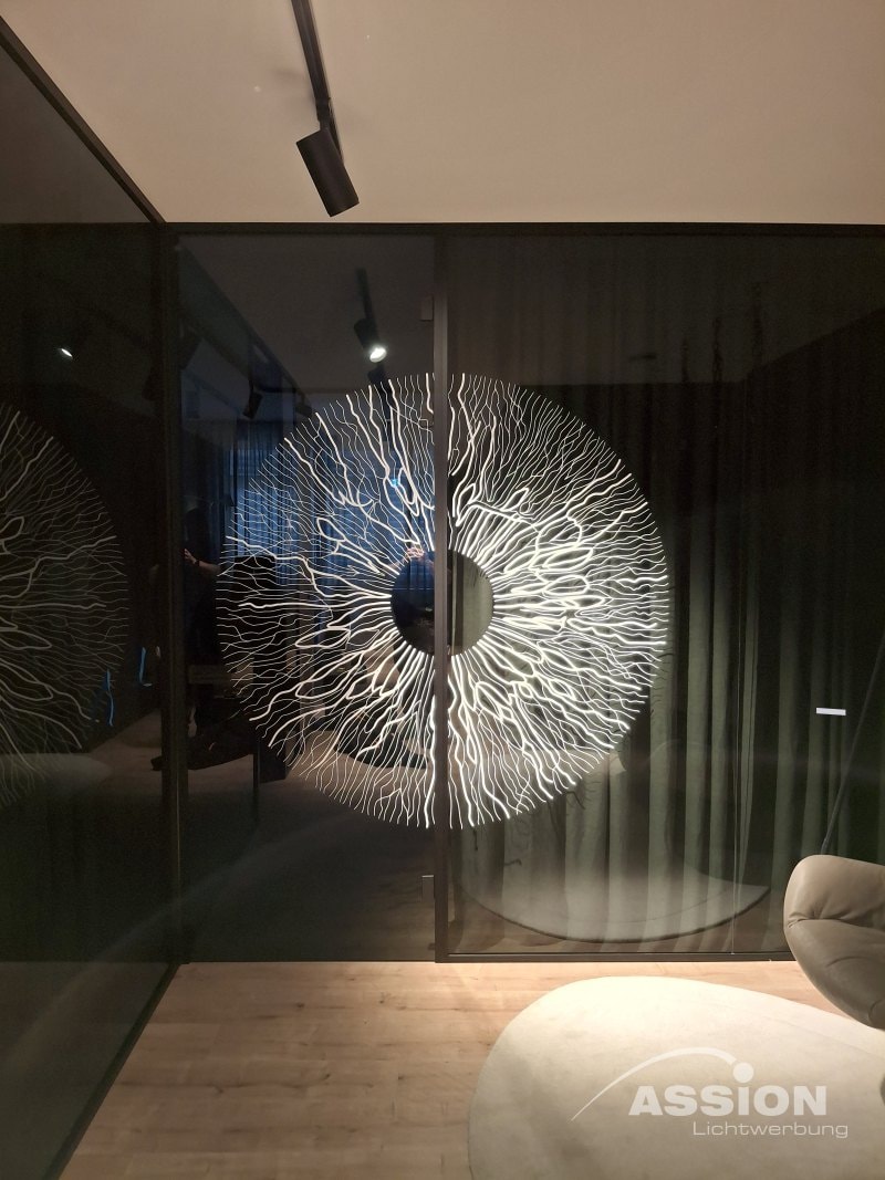 Folienbeklebungen (1) XXX Ein großes, kreisrundes, abstraktes Wandkunstwerk, das einem Auge mit verschlungenen weißen Linien ähnelt, wird auf einer Glaswand in einem modernen Raum mit Holzfußboden ausgestellt und zeigt kreative Folienbeklebungen.