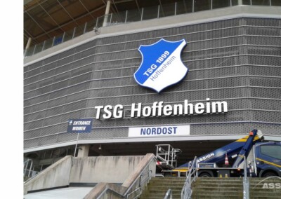 Der Eingang des Stadions der TSG Hoffenheim mit dem Vereinslogo über dem Schriftzug "TSG Hoffenheim" und einem in der Nähe des Nordost-Eingangs geparkten LKW.
