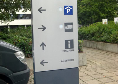 Hinweisschild der IHK Darmstadt Rhein Main Neckar mit Park-, Liefer-, Einfahrts- und Ausfahrtshinweisen mit Pfeilsymbolen auf einem Außenparkplatz.