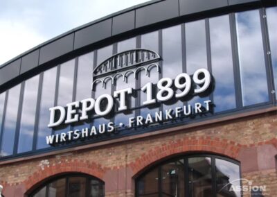 Eine Gebäudefassade mit der Aufschrift "DEPOT 1899 Wirtshaus Frankfurt" mit einer Backsteinfassade und einem modernen Glasoberteil.