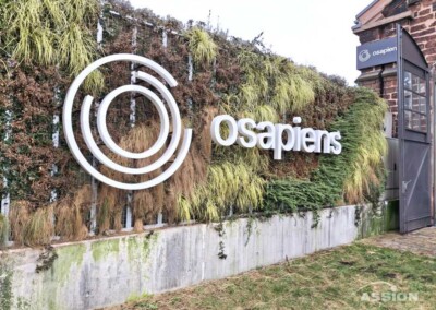 Eine grüne Wand mit dem Logo und dem Namen von Osapiens in weißer Schrift neben einer Glastür.