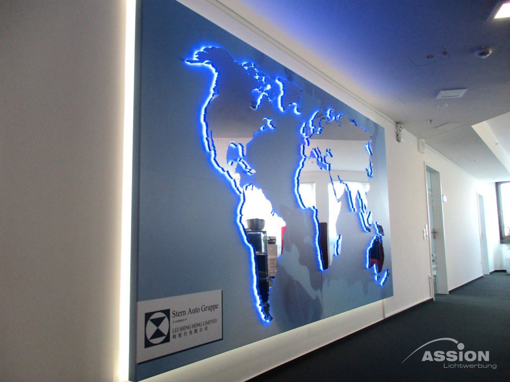 Eine Weltkarten-Wandinstallation mit blauer LED-Beleuchtung und einer Firmenplakette präsentiert Sonderanlagen in einem modernen Büroflur.