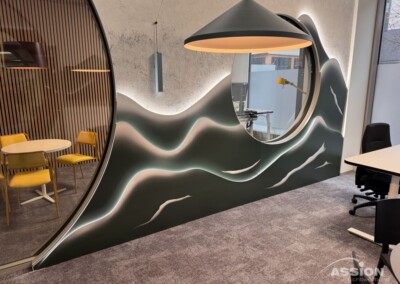 Moderner Büroraum mit einem großen runden Fenster in einer gewellten Wand, einer Pendelleuchte, einem runden Tisch mit gelben Stühlen und einem Schreibtisch mit Bürostuhl.