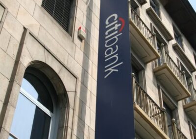Vor einem Steingebäude mit Balkonen und Fenstern hängt ein vertikales Citibank-Schild.