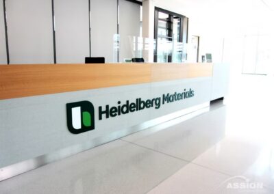 Empfangsschalter mit dem Schild "Heidelberg Materials" in einer hellen, modernen Bürohalle.